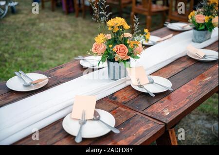 Rustic wedding style, Wooden dining table with flowers decoration and tableware set Stock Photo