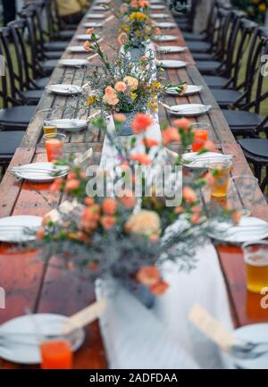 Rustic wedding style, Wooden dining table with flowers decoration and tableware set Stock Photo