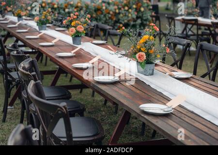 Rustic wedding style, Wooden dining table with flowers decoration and tableware set Stock Photo
