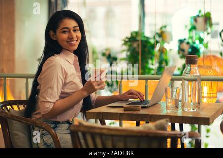 Pretty lady posing with latte in front of the laptop Stock Photo