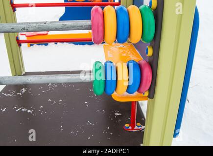 Large colored children's abacus, plastic rings on metal frames, winter Playground covered with snow Stock Photo