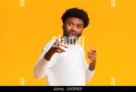 Excited black man greeting happily, indicating to camera Stock Photo