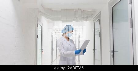 Female doctor in protective wear reading analysis results Stock Photo