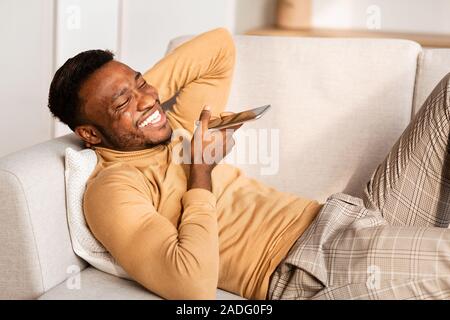 Man Using Phone Voice Assistant Lying On Couch At Home Stock Photo