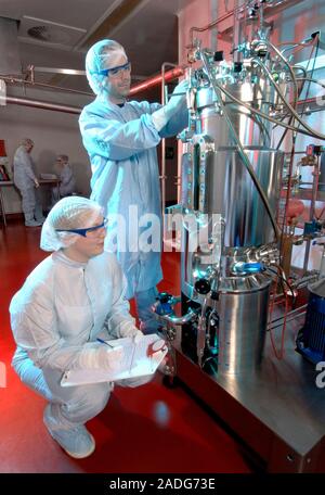 Microbial fermentation. Workers in clean room suits inspecting a microbial fermentation unit. The fermentation unit provides optimal growing condition Stock Photo