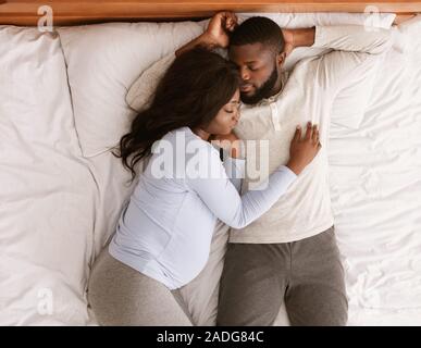 Lovely pregnant couple sleeping together at home Stock Photo