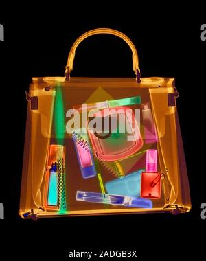 Handbag. Coloured X-ray of a woman's handbag showing the contents. The contents include various cosmetics: perfume bottle, eyeliner pencil, mascara wi Stock Photo