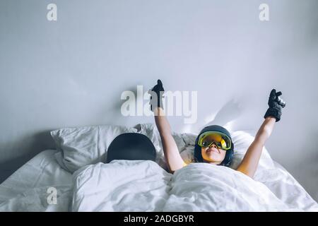 woman sleeping in bed with snowboard dreaming about ski at snow mountains Stock Photo