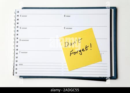 Diary reminder. Post-it note placed on a diary to remind the diary owner not to forget an appointment. Stock Photo