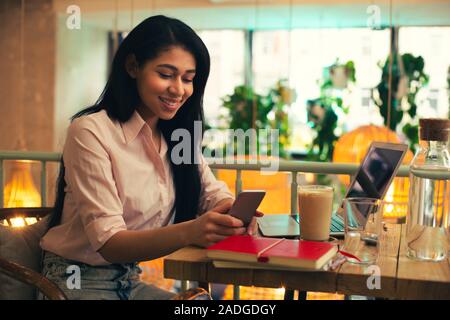 Busy woman using smartphone in the cafe and smiling Stock Photo