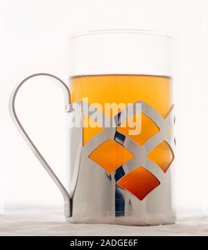 Glass of tea in a metal holder. Tea is an infusion of the leaves of the tea plant (Camellia sinensis) and contains the stimulant caffeine. This is gre Stock Photo