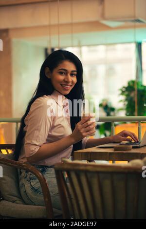 Long haired lady sitting with coffee drink and smiling Stock Photo