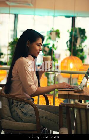 Calm student using laptop and drinking latte Stock Photo
