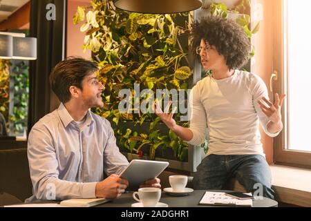 Male partners talking about business plan during coffee break Stock Photo