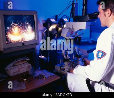 Comparing used bullet cartridges. Forensic scientist using a microscope to compare markings on the back of handgun cartridge shells. The shells held b Stock Photo