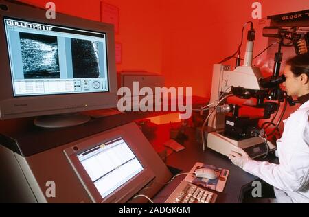 Comparing bullets. Forensic scientist using a microscope to compare markings on bullets. The barrel of gun has grooves on the inside that make a bulle Stock Photo