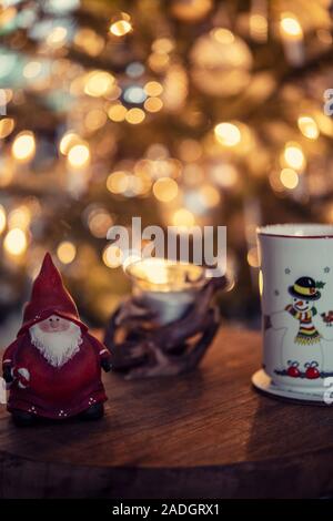 Cup and ornaments on a table in front of a Christmas tree Stock Photo