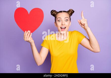 Photo of cheerful white casual positive cute pretty nice girlfirend having come up with idea whom to gift big red heart she holds isolated over violet Stock Photo