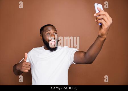 Photo of cheerful positive attractive handsome expressing positive emotions taking selfie showing you thumb up screaming isolated over pastel brown Stock Photo