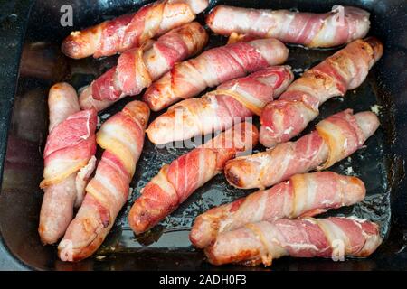 Cooked pigs in blankets, a traditional English Christmas food of sausages wrapped in bacon Stock Photo