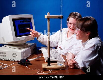 Chemistry experiment. Students performing a titration, which is monitored by a computer via a temperature probe (lower right). The computer makes it e Stock Photo
