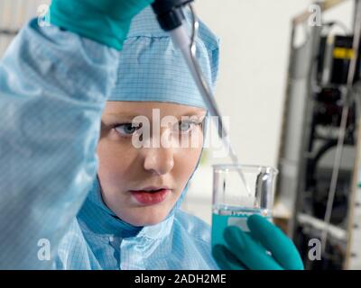 Cleanroom facility. Technician at work in a cleanroom facility. A cleanroom is an environment used in manufacturing or scientific research that has a Stock Photo