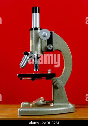 Light microscope. Side view of a light microscope with a single eyepiece (monocular). The sample is placed on a glass slide at lower centre. Below the Stock Photo