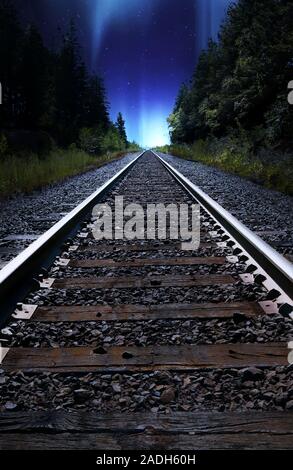 Looking down train tracks at night with Northern Lights in Sky, Alberta, Canada Stock Photo