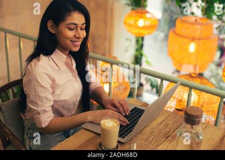Pleased young woman feeling good while working on her laptop Stock Photo