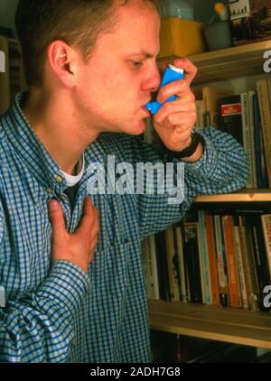 Asthma relief. Young man using an inhaler to control an asthma attack. Asthma attacks vary in severity from breathlessness, dry cough, wheezing, or a Stock Photo