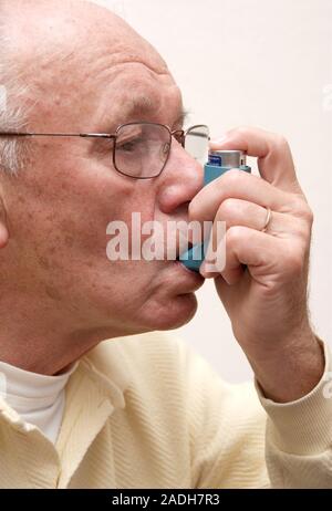 MODEL RELEASED. Asthma attack. Elderly man using an inhaler during an asthma attack. Asthma is a disease of the respiratory system. Attacks can be tri Stock Photo