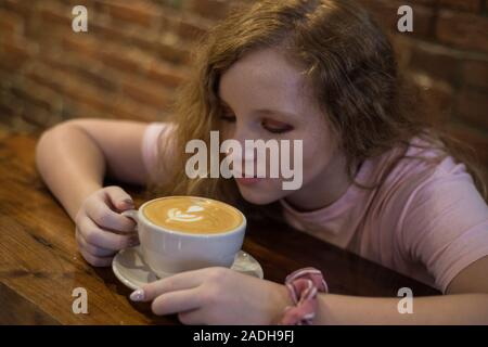 A girl looking at a cappuccino drink. Stock Photo