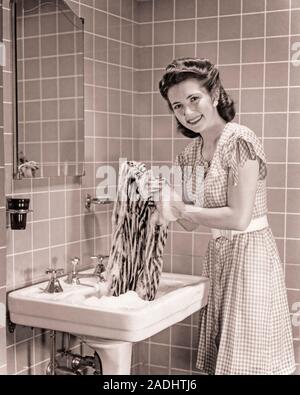 Doing the laundry in the 1960s. A lady is using a washboard to clean the  dirty laundry. The tool was designed for hand washing clothing rubbing them  agains the series of ridges