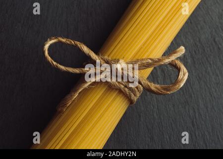Neat rope bow on the top of uncooked pasta bunch Stock Photo