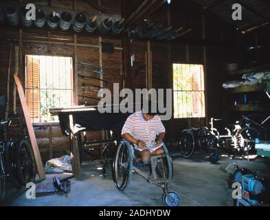 Disability. Disabled man working in his wheelchair repair and refurbishment workshop. This man has had both his legs amputated after an injury sustain Stock Photo
