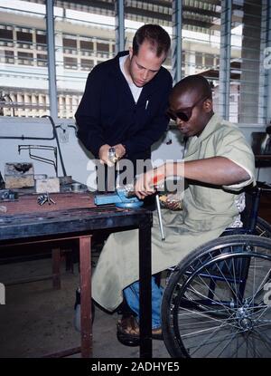 Wheelchair workshop. Wheelchair designer helping a student on a wheelchair technologists training course in Tanzania. The course covers all aspects of Stock Photo