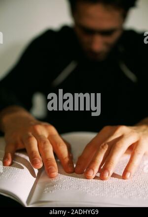 Braille. Blind man moving his fingers across a page from a book written in braille. The braille writing and reading system was devised by the French t Stock Photo