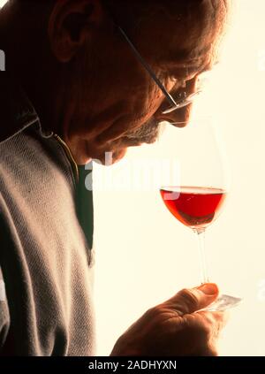 Wine drinking. Elderly man sniffs the odour of red wine before having a drink. Stock Photo