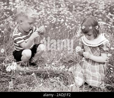 1950s LITTLE BOY AND GIRL BROTHER AND SISTER IN FIELD OF DAISIES MAKING CROWNS PULLING PETALS PLAYING LOVE ME LOVE ME NOT  - j2073 HAR001 HARS FEMALES BROTHERS RURAL HEALTHINESS FRIENDSHIP FULL-LENGTH SCENIC INSPIRATION MALES SERENITY SIBLINGS SPIRITUALITY CONFIDENCE SISTERS B&W DAISIES ME WIDE ANGLE PETALS HAPPINESS WELLNESS DISCOVERY AND O RECREATION NOT IN CROWNS SIBLING CONCEPTUAL STYLISH COOPERATION CREATIVITY GROWTH JUVENILES TOGETHERNESS BLACK AND WHITE CAUCASIAN ETHNICITY HAR001 OLD FASHIONED Stock Photo