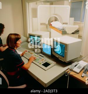 MODEL RELEASES AVAILABLE. Computed tomography (CT) brain scanning, showing scanner and patient in background and radiographers working at the scanner' Stock Photo