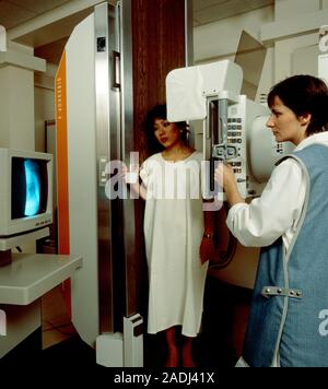 MODEL RELEASES AVAILABLE. Woman undergoing barium meal X-ray examination, photographed holding a beaker containing a suspension of white barium sulpha Stock Photo