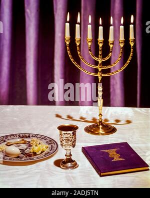 1980s HEBREW PASSOVER SYMBOLS BRASS MENORAH CANDLES SILVER KIDDUSH CUP SEDER PLATE AND COPY OF THE HAGGADAH - kr29438 PHT001 HARS HEBREW JEWISH JUDAIC JUDAISM OLD FASHIONED REPRESENTATION Stock Photo