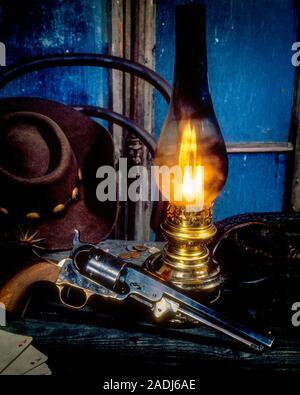 1960s 1970s OLD WEST MOVIE MOTIF COLT 1851 PERCUSSION REVOLVER HAND GUN COWBOY HAT PLAYING CARDS LIGHTED KEROSENE HURRICANE LAMP - ks17886 PHT001 HARS FIREARMS HAND GUN 1851 LIGHTED MOTIF OLD FASHIONED Stock Photo