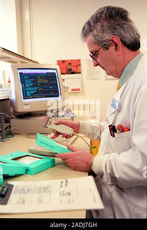 Stored blood plasma. Technician scanning units of fresh, frozen blood plasma. He is using a barcode scanner to read unique barcodes on the packaging t Stock Photo