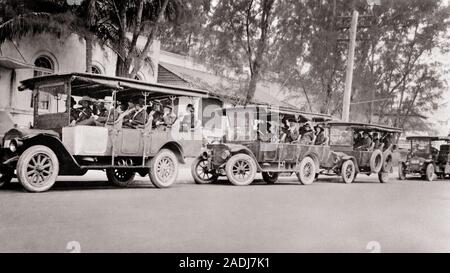 1910s LINE OF FULL OPEN-SIDED TOUR TOURIST BUSES PARKED ALONG CURB  - m9158 LEF001 HARS IN LINE BUSES COOPERATION TOGETHERNESS TRANSIT BLACK AND WHITE MOTOR VEHICLES OLD FASHIONED Stock Photo