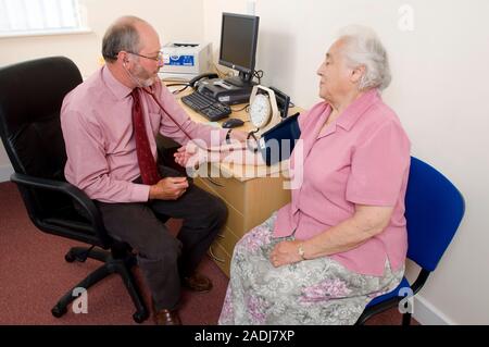 MODEL RELEASED. Measuring blood pressure. Senior woman having her blood pressure checked by a doctor using a sphygmomanometer. A pressure gauge (dial Stock Photo