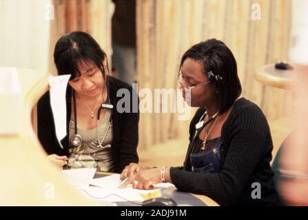 Hospital doctors conferring about medical records. The hospital is part of England's National Health Service (NHS). Photographed at St Richard's Hospi Stock Photo