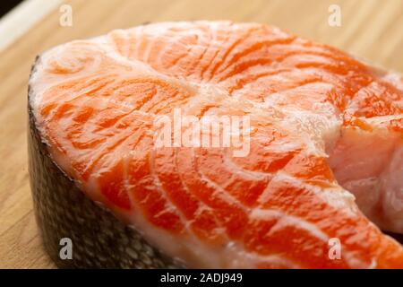 Raw red salmon slice lying on wooden surface Stock Photo