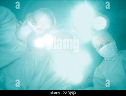 Surgery. Semi-conscious patient's view of a surgical team about to perform surgery in an operating theatre. Stock Photo