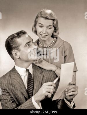 1950s 1960s COUPLE REVIEWING A LIST MAN HOLDING PAPER  AND PEN WOMAN LEANING ON HIS SHOULDER - s8913 HAR001 HARS INDUSTRY OLD FASHION STYLE COMMUNICATION FRIEND YOUNG ADULT TEAMWORK TOUCH INFORMATION ASSISTANT PLEASED JOY LIFESTYLE CLERK FEMALES STUDIO SHOT MANAGER COPY SPACE FRIENDSHIP HALF-LENGTH LADIES PERSONS MALES CONFIDENCE EXECUTIVES B&W SUIT AND TIE HAPPINESS CHEERFUL DISCOVERY HIS AND CHOICE LOW ANGLE QUESTION PRIDE OFFICE WORKER OCCUPATIONS SMILES BOSSES CONNECTION REVIEWING GAL FRIDAY ADMINISTRATOR FRIENDLY JOYFUL SECRETARIES STYLISH AMANUENSIS COOPERATION MANAGERS MID-ADULT Stock Photo